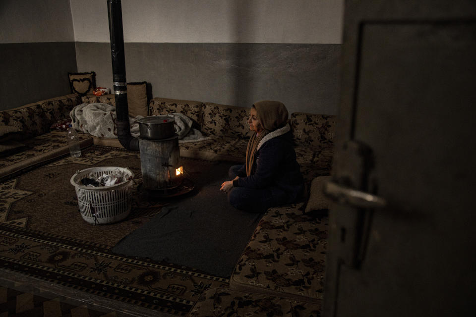 A woman sits by a wood heater in Aleppo, Syria, Sunday, Dec. 15, 2022. Syria's economy has hit its lowest point since the country's civil war began nearly 12 years ago, with severe fuel shortages in both government and rebel-held areas, spiraling inflation and the Syrian currency hitting an all-time low on the black market. (AP Photo/Baderkhan Ahmad)