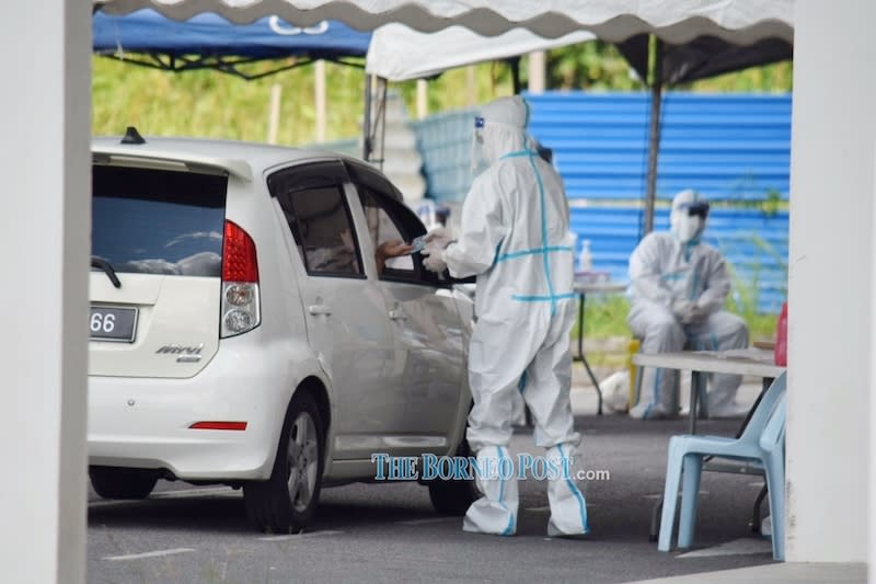 File picture shows medical personnel conducting health checks at Taman Univista where a cluster has emerged. — Borneo Post Online pic