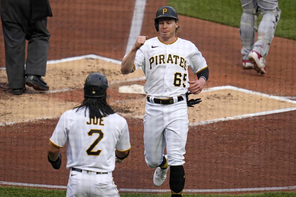 Pittsburgh Pirates' Jack Suwinski (65) is greeted by Connor Joe (2) after both scored on a single by Mark Mathias off Cincinnati Reds starting pitcher Graham Ashcraft during the second inning of a baseball game in Pittsburgh, Friday, April 21, 2023. (AP Photo/Gene J. Puskar)