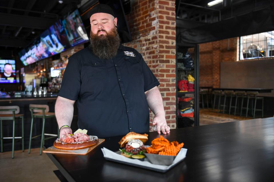 Adam Story, general manager at Main Street Pub, delivers new menu items to a table in Spartanburg, S.C., on Wednesday, April 10, 2024.