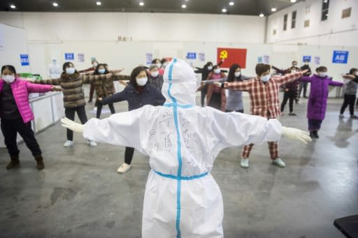 A medical staffer leads patients who have displayed mild symptoms of the COVID-19 illness in group exercises at a hospital in Wuhan, the epicenter of the global outbreak