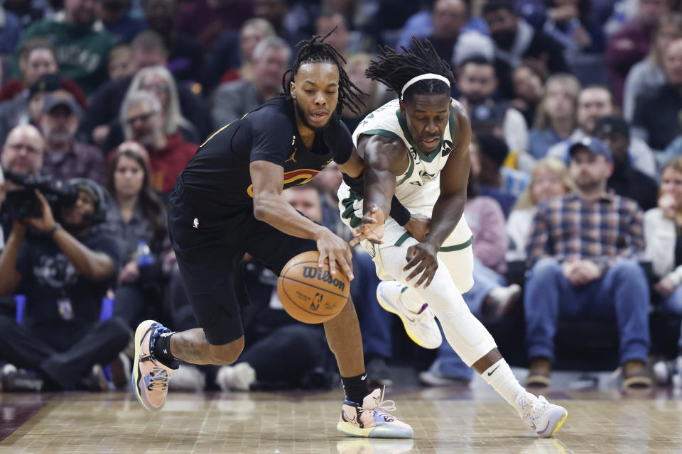 Cleveland Cavaliers guard Darius Garland, left, controls a loose ball against Milwaukee Bucks guard Jrue Holiday during the first half of an NBA basketball game, Saturday, Jan. 21, 2023, in Cleveland. (AP Photo/Ron Schwane)