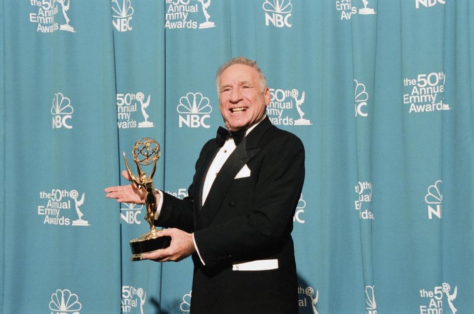 mel brooks is wearing a black tuxedo and posing for a photo while holding one of his emmy awards