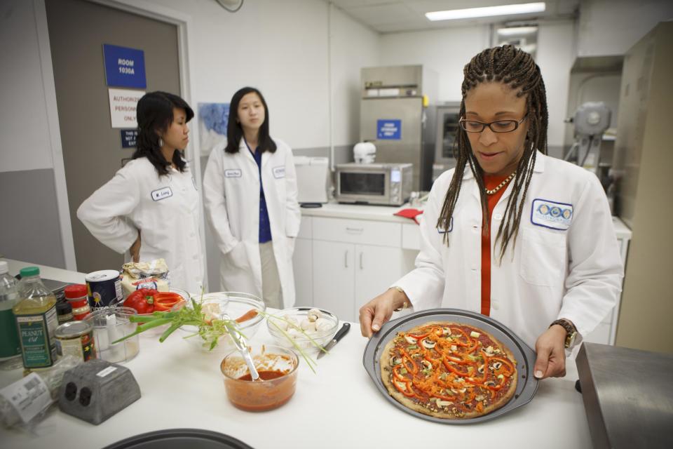 Lockeed Martin senior research scientist Maya Cooper shows a vegan pizza developed at NASA's Advanced Food Technology Project at Johnson Space Center in Houston Tuesday, July 3, 2012. NASA is currently planning a mission to Mars, which has gravity, so more options for food preparation, like chopping vegetables, are available as opposed to the dehydrated fare of current space missions. (AP Photo/Michael Stravato)