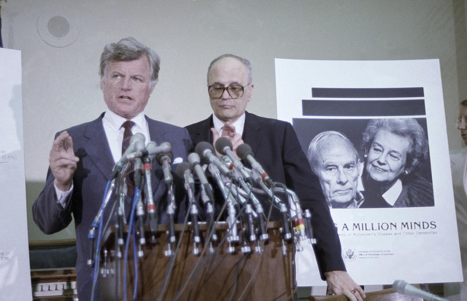 FILE- In this April 7, 1987 file photo, Sen. Edward Kennedy, D-Mass., left, and John Dingell, D-Mich. hold a news conference at Capitol Hill, in Washington, to release a report on Alzheimers disease. Dingell, the longest-serving member of Congress in American history who mastered legislative deal-making and was fiercely protective of Detroit's auto industry, has died at age 92. Dingell, who served in the U.S. House for 59 years before retiring in 2014, died Thursday, Feb. 7, 2019, at his home in Dearborn, said his wife, Congresswoman Debbie Dingell. (AP Photo/Charles Tasnadi, File)