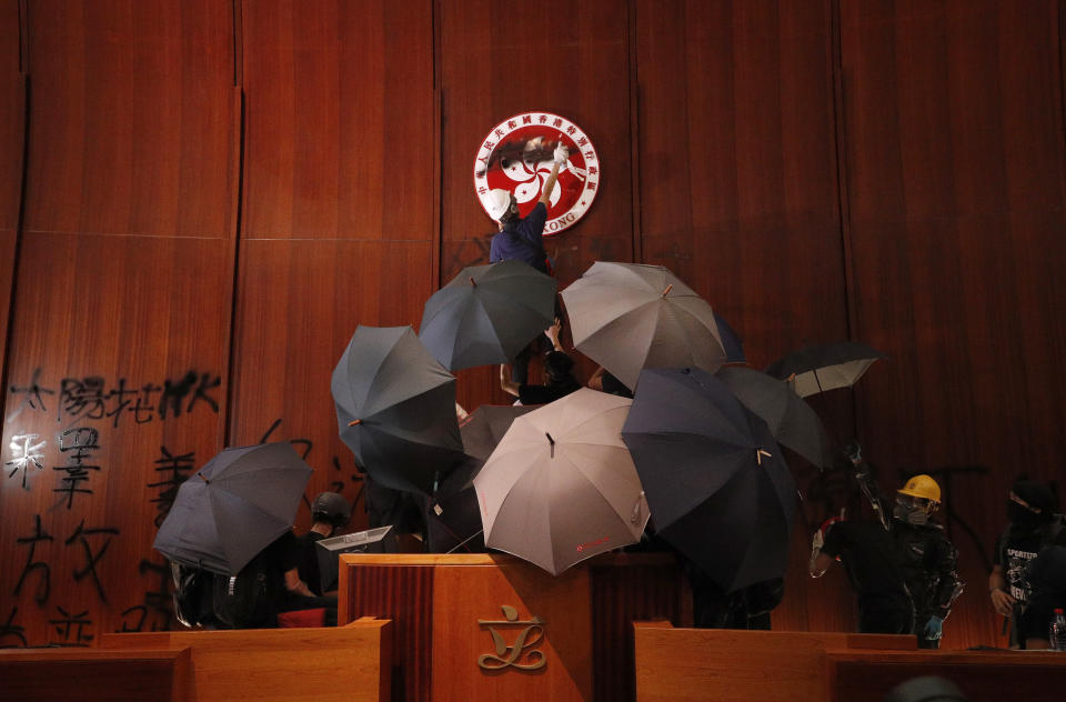 Protesters deface the Hong Kong logo at the Legislative Council to protest against the extradition bill in Hong Kong, Monday, July 1, 2019. The extradition law has aroused concerns that this legislation would undermine the city's independent judicial system as it allows Hong Kong to hand over fugitives to the jurisdictions that the city doesn't currently have an extradition agreement with, including mainland China, where a fair trial might not be guaranteed. (AP Photo/Vincent Yu)