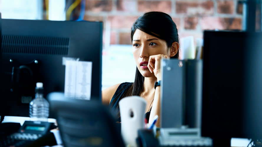 A worried woman looking at a computer screen.