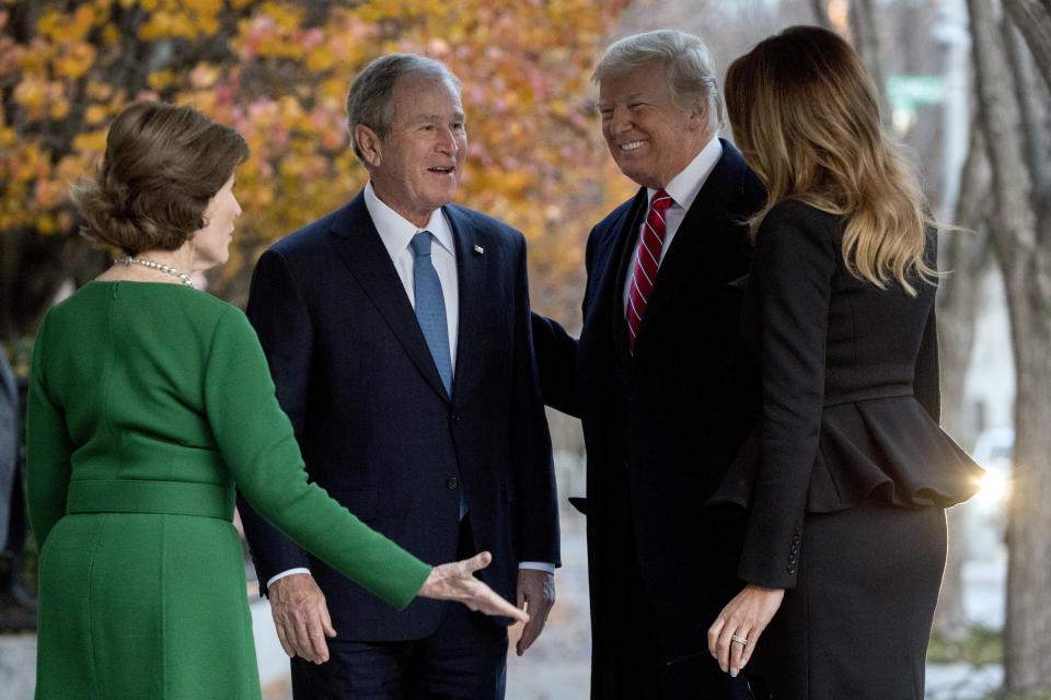 President Donald Trump and first lady Melania Trump are greeted by former President George Bush and former first lady Laura Bush outside the Blair House across the street from the White House in Washington, Tuesday, Dec. 4, 2018. (AP Photo/Andrew Harnik)