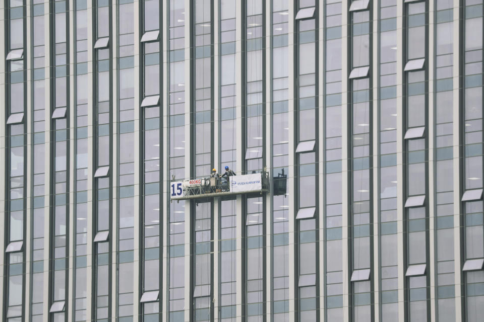 Workers stand on a suspended platform hung by the side of a high-rise building in Hanoi, Vietnam, Wednesday, March 29, 2023. Vietnam's economy slowed sharply in the first quarter of this year, with growth coming in at a much weaker than expected 3.3%, as its exporters were hit by rising costs and weaker demand, the General Statistics Office reported Wednesday. (AP Photo/Hau Dinh)