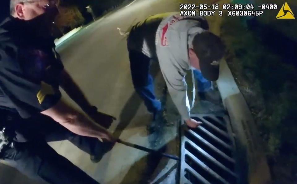 North Canton police Sgt. Ron Mizner, along with a resident, uses a crowbar to lift a storm sewer grate to rescue 12 trapped ducklings on the city's southwest side.