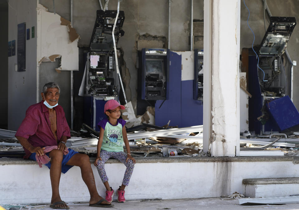 Residents sit at a bank lacking windows and with destroyed bank teller machines two days after the passage of Hurricane Otis as a Category 5 storm in Acapulco, Mexico Friday, Oct. 27, 2023. (AP Photo/Marco Ugarte)