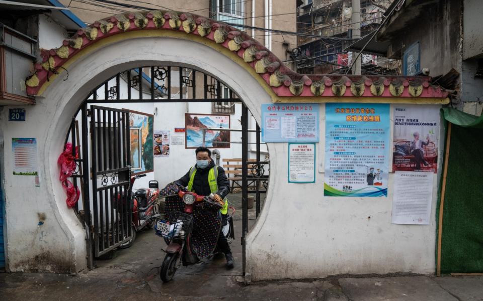 Posters reminding people to stay healthy and vigilant are seen at the gate of a residential compound in Wuhan - Yan Cong for The Telegraph