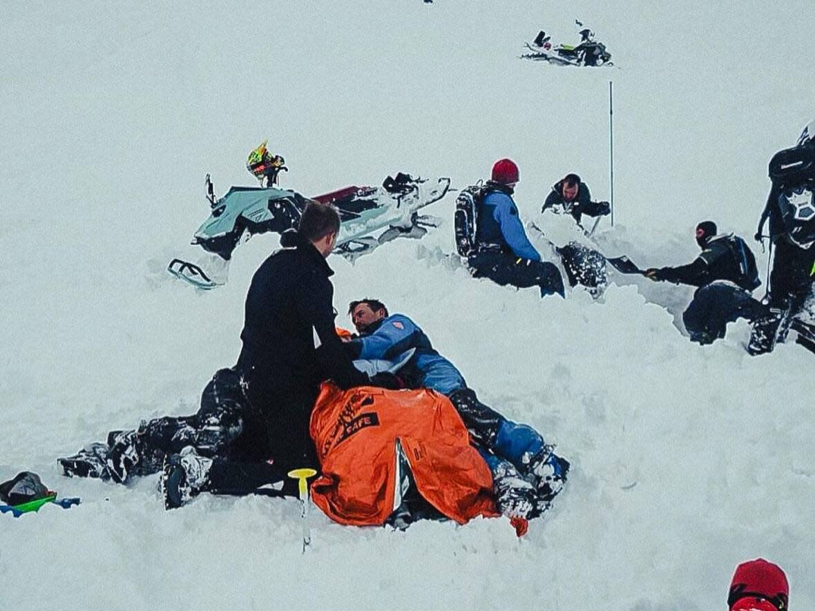 A photo posted by Great Canadian Tours shows rescue operations of a snowmobiler who was trapped in mountain snow near Revelstoke, B.C., on Feb. 26, 2024. (Great Canadian Tours - image credit)