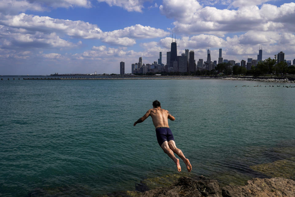 FILE - A man jumps into Lake Michigan to cool off on July 20, 2022, with the downtown Chicago skyline seen in the background. Studies predict the Great Lakes and other large freshwater bodies around the world will move toward acidity as they absorb excess carbon dioxide from the atmosphere, which also causes climate change. Experts say acidification could disrupt aquatic food chains and habitat. (AP Photo/Kiichiro Sato, File)