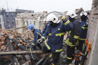 Ukrainian emergency workers clear the rubble on the roof of a residential building which was hit by a Russian rocket at the city center of Kharkiv, Ukraine, Monday, Jan. 30, 2023. Russian shelling killed at least five people and wounded 13 others during the previous 24 hours, Ukrainian authorities said Monday as the Kremlin’s and Kyiv’s forces remained locked in combat in eastern Ukraine. (AP Photo/Andrii Marienko)