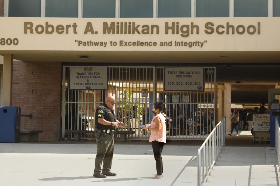 A Long Beach Unified School District safety officer speaks to a woman outside Robert A. Millikan High School