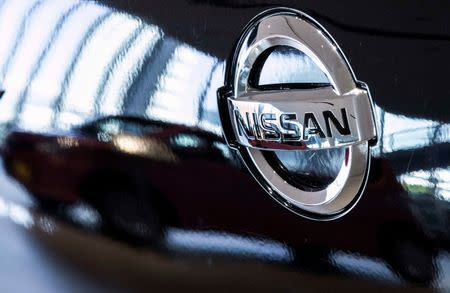 A car is reflected in the bonnet of a Nissan car in the showroom at Nissan's global headquarters in Yokohama south of Tokyo, February 9, 2015. REUTERS/Thomas Peter