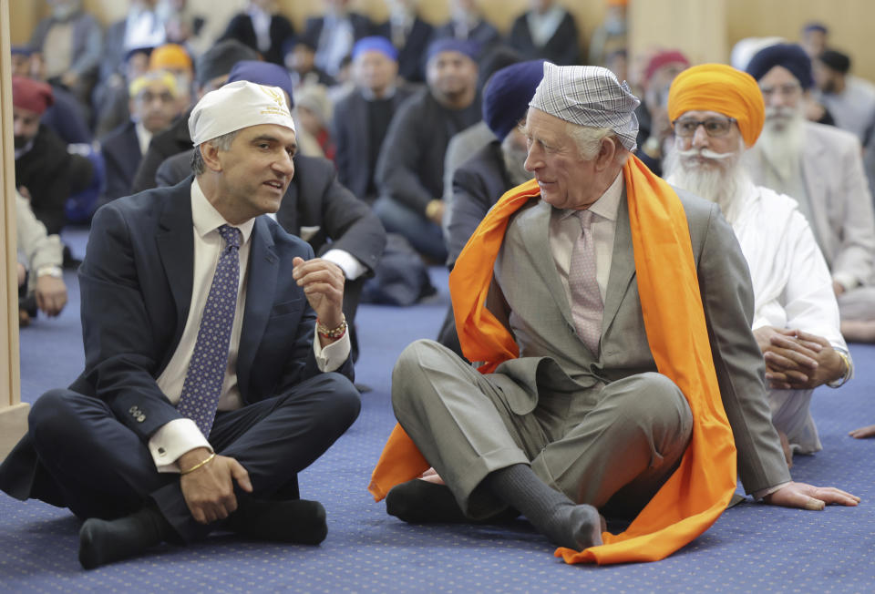 Britain's King Charles III, right, speaks with Professor Gurch Randhawa, a member of the Sikh Congregation, as they sit on the floor in the Prayer Hall during the king's visit to the newly built Guru Nanak Gurdwara, in Luton, England, Tuesday, Dec. 6, 2022. (Chris Jackson/Pool Photo via AP)