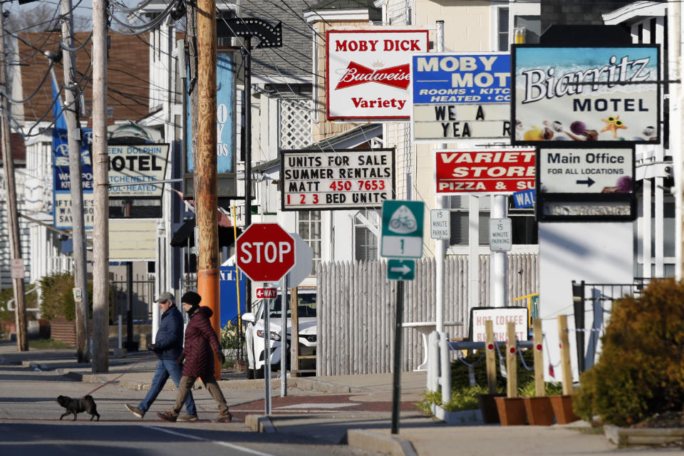 A couple walks by a row of closed motels, Wednesday, April 29, 2020, in Old Orchard Beach, Maine. Gov. Janet Mills on Tuesday announced tentatives plans to allow for lodging, campgrounds and the reopening of bars on July 1. Many businesses have been closed by the coronavirus pandemic. (AP Photo/Robert F. Bukaty)