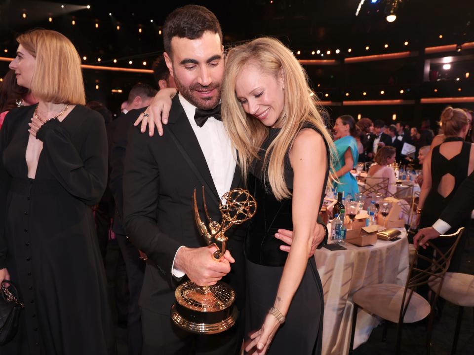 brett goldstein and juno temple pose with juno's arm around goldstein, who is holding his emmy award