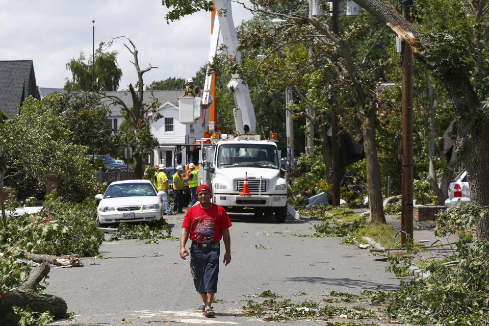 A man walks amid cleanup crews on Vinal Street in Revere, Massachusetts, July 28, 2014. Police and emergency crews in Revere, outside Boston scrambled to clean up after a rare tornado touched down on Monday, downing power lines, damaging homes and overturning at least one car. The National Weather Service confirmed that a tornado touched down during a storm that brought heavy rains, lightning and flooding to Boston and many of its northern suburbs. State emergency management officials said they were not aware of major injuries or fatalities from the storm. (REUTERS/Dominick Reuter )