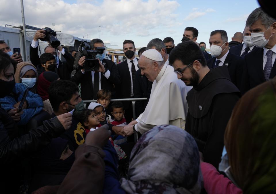 Pope Francis meets migrants during his visit at the Karatepe refugee camp, on the northeastern Aegean island of Lesbos, Greece, Sunday, Dec. 5, 2021. Pope Francis is offering comfort migrants at a refugee camp on the Greek island of Lesbos. He is blasting what he says is the indifference and self-interest shown by Europe "that condemns to death those on the fringes." (AP Photo/Alessandra Tarantino)