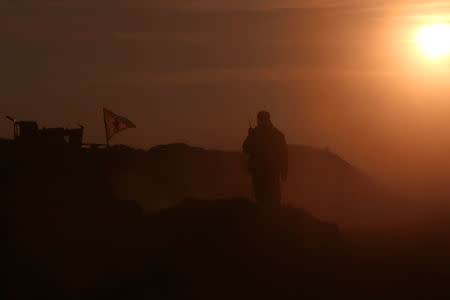 A Syrian Democratic Forces fighter stands near a flag in northern Raqqa province, Syria. REUTERS/Rodi Said