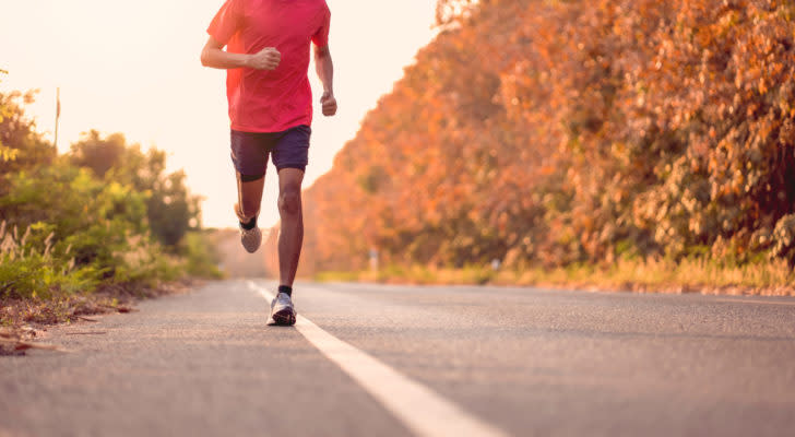 A photograph of a person running along the side of a road.