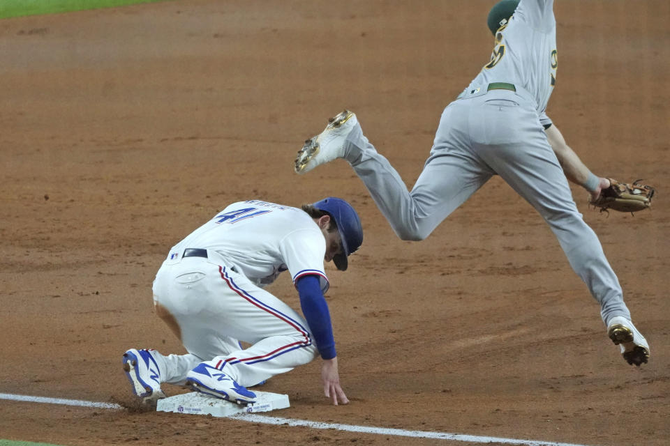 Texas Rangers' Eli White slides safely into third base past Oakland Athletics third baseman Matt Chapman as he advances on a wild pitch in the second inning of a baseball game Thursday, June 24, 2021, in Arlington, Texas. (AP Photo/Louis DeLuca)