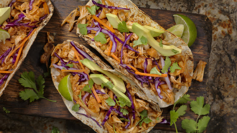 Jackfruit tacos on a wooden slab with lime