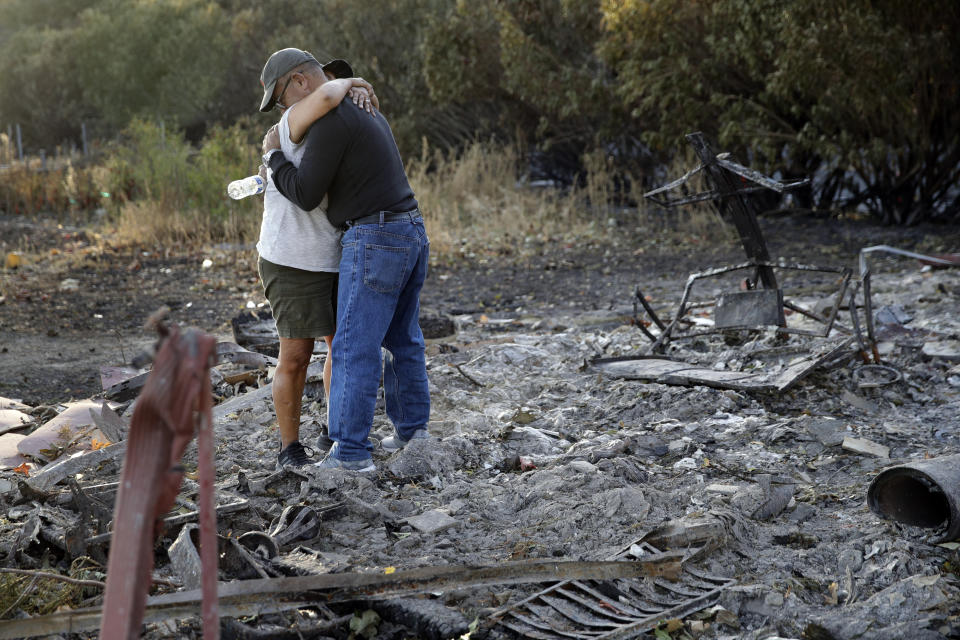 Justo and Bernadette Laos hug while looking through the charred remains of the home they rented that was destroyed by the Kincade Fire near Geyserville, Calif., Thursday, Oct. 31, 2019. The fire started last week near the town of Geyserville in Sonoma County north of San Francisco. (AP Photo/Charlie Riedel)