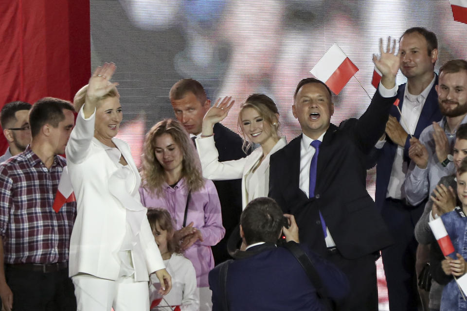 Incumbent President Andrzej Duda, right, his wife Agata Kornhauser-Duda, left, and daughter Kinga, wave to supporters in Pultusk, Poland, Sunday, July 12, 2020. An exit poll in Poland's presidential runoff election shows a tight race that is too close to call between the conservative incumbent, Andrzej Duda, and the liberal Warsaw mayor, Rafal Trzaskowski.(AP Photo/Czarek Sokolowski)