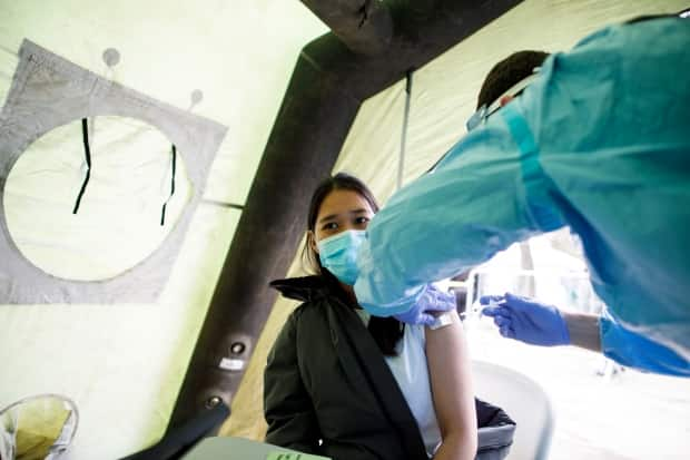 A woman is vaccinated with a dose of the  Moderna COVID-19 vaccine at a pop-up vaccine clinic in Toronto's Jane and Finch neighbourhood, in the M3N postal code, on Saturday, April 17, 2021. Despite rates of COVID-19 deaths and hospitalizations far exceeding other areas of the city, residents of the M3N postal code continue to struggle with the lowest vaccination rates in Toronto. 