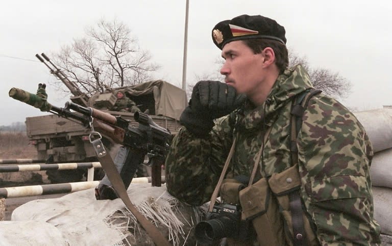 A Russian special police officer with a Zenit camera around his neck seen standing guard in February 2000 at a Chechen-Ingush border checkpoint