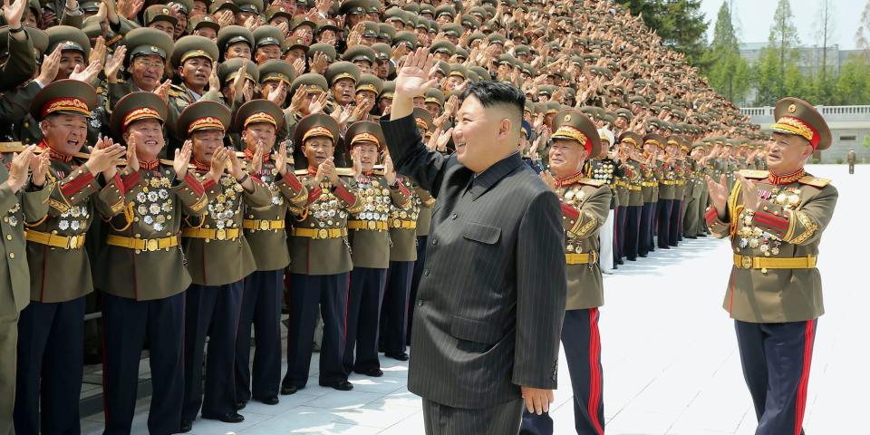 Kim Jong Un waves at a crowd of applausing North Korean soldiers in a black suit, July 2021 in Pyongyang