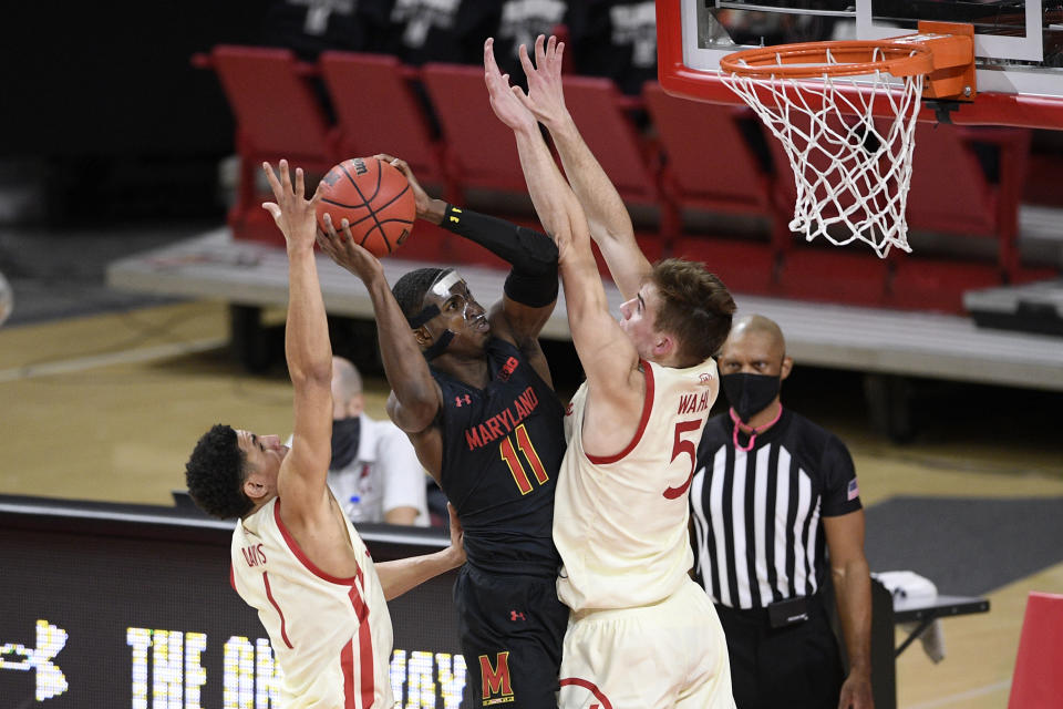 Maryland guard Darryl Morsell (11) goes to the basket between Wisconsin guard Jonathan Davis (1) and forward Tyler Wahl (5) during the first half of an NCAA college basketball game, Wednesday, Jan. 27, 2021, in College Park, Md. Morsell was fouled on the play. (AP Photo/Nick Wass)