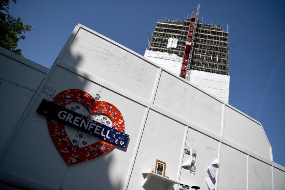 Covers go up on the charred remains of the tower in west London (EPA)