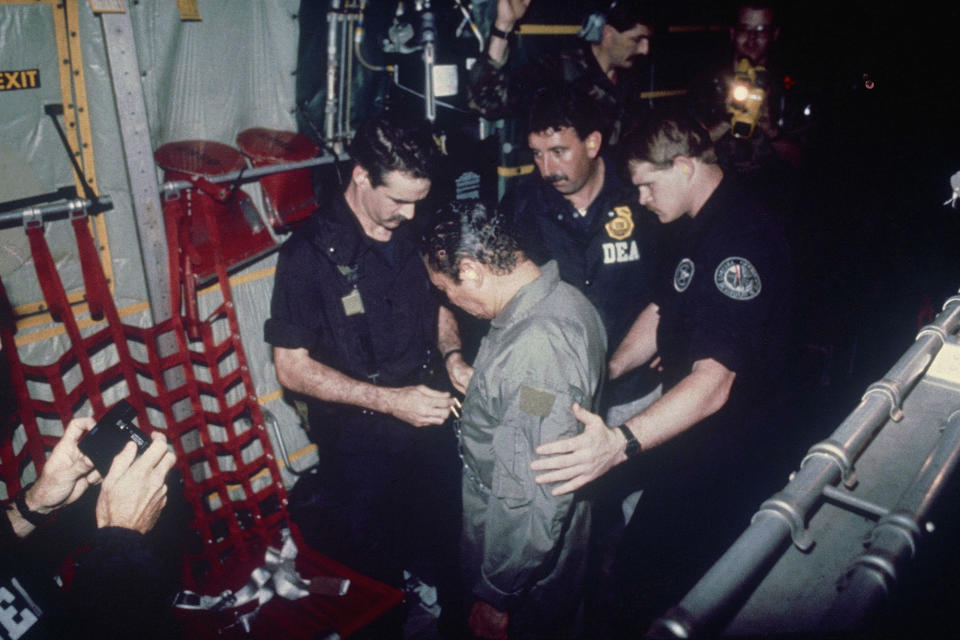 <p>Manuel Noriega watches as U.S. Drug Enforcement Agents place chains around his waist aboard a C-130 transport plane, Jan. 4, 1990. (AP Photo) </p>