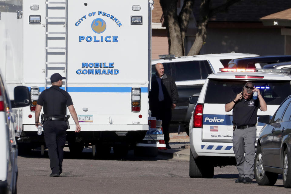 Law enforcement officers stand outside the scene of a deadly shooting early Monday, March 30, 2020, in Phoenix. Phoenix police say one of their commanders was killed and two other officers were wounded as they responded to a domestic dispute. Authorities say Cmdr. Greg Carnicle and officers were called to a home in the northern part of Phoenix Sunday night over a roommate dispute when the suspect refused to cooperate and shot them. The suspect was not identified and was pronounced dead at the scene. (AP Photo/Matt York)