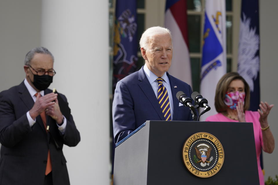 President Joe Biden speaks about the American Rescue Plan, a coronavirus relief package, in the Rose Garden of the White House, Friday, March 12, 2021, in Washington. Senate Majority Leader Chuck Schumer of N.Y., left, and House Speaker Nancy Pelosi of Calif., listen. (AP Photo/Alex Brandon)
