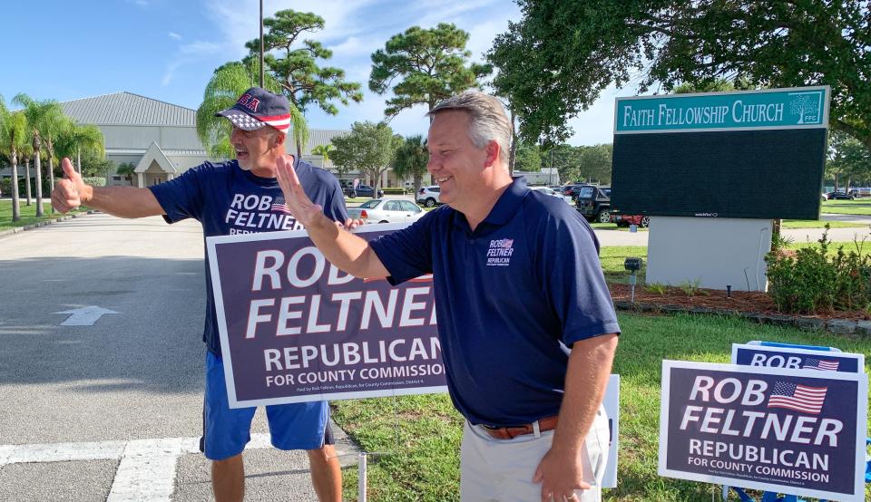 Rob Feltner, right, District 4 candidate for Brevard County Commission, waves at voters outside Precinct 427 at Faith Fellowship Church in Melbourne.