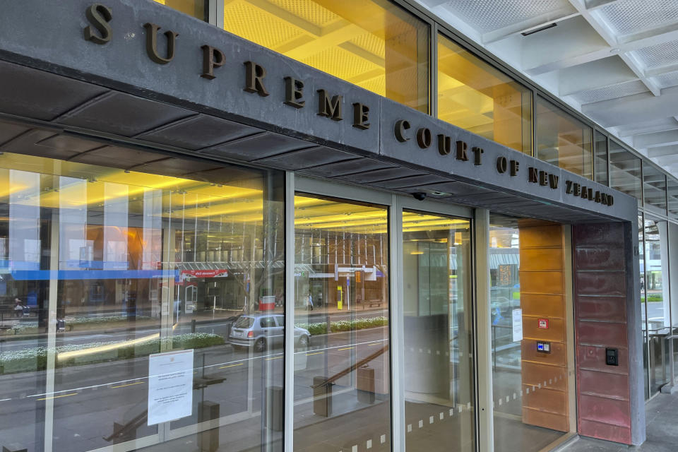 Glass doors line the entrance way of the Supreme Court in Wellington, New Zealand, Thursday, August 25, 2022. Exclusive documents obtained by The Associated Press show that New Zealand tax payers could bear the cost of millions of dollars to monitor the treatment of a soon to be extradited murder suspect to Shanghai. (AP Photo/Nick Perry)