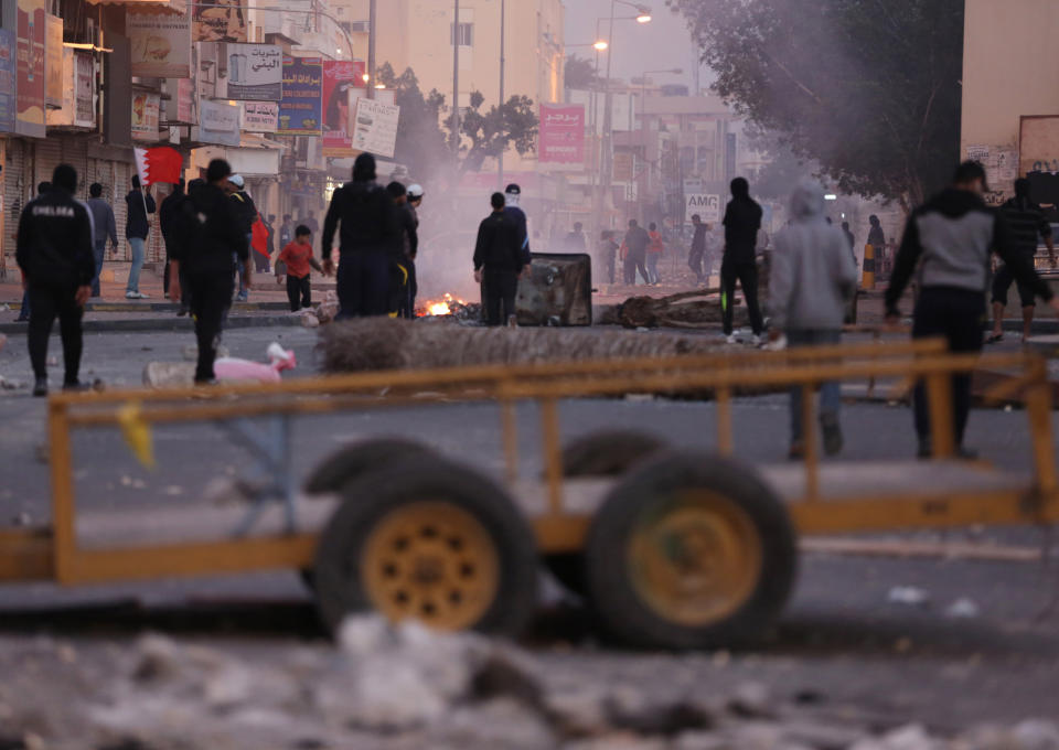 Bahraini anti-government protesters watch for riot police between clashes in the debris-filled main street of Musalla, Bahrain, Thursday, Feb. 13, 2014. Rubbish and oil smeared on the road are meant to deter police jeeps from entering the village, where shops were shuttered in observance of a general strike called by anti-government groups in the run-up to Friday's third anniversary of the pro-democracy uprising in the Gulf island kingdom. (AP Photo/Hasan Jamali)