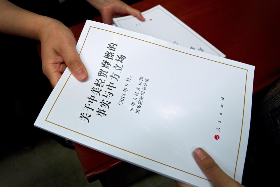 FILE - In this Sept. 25, 2018, file photo, a government officer distributes copies of a report on "the Facts and China's Position on China-U.S. Trade Friction" to journalists during a press conference at the State Council Information Office in Beijing. (AP Photo/Andy Wong, File)