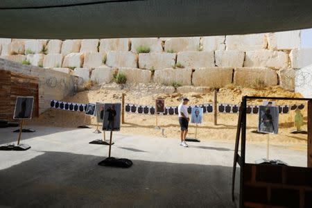 A tourist looks at posters placed near shooting targets during a two hour "boot camp" experience, at "Caliber 3 Israeli Counter Terror and Security Academy" in the Gush Etzion settlement bloc south of Jerusalem in the occupied West Bank July 13, 2017. Picture taken July 13, 2017. REUTERS/Nir Elias