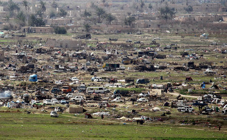 Islamic State members walk in the last besieged neighborhood in the village of Baghouz, Deir Al Zor province, Syria March 17, 2019. REUTERS/Stringer