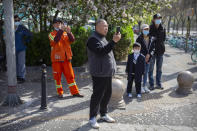 People pause at an intersection during a national moment of mourning for victims of the coronavirus, in Beijing on Saturday, April 4, 2020. With air raid sirens wailing and flags at half-staff, China on Saturday held a three-minute nationwide moment of reflection to honor those who have died in the coronavirus outbreak, especially "martyrs" who fell while fighting what has become a global pandemic. (AP Photo/Mark Schiefelbein)