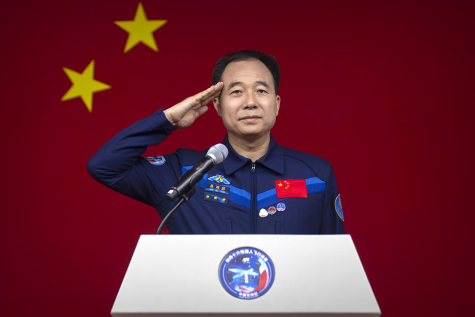 Jing Haipeng, a Chinese astronaut for the upcoming Shenzhou-16 mission, salutes behind glass during a meeting of the press at the Jiuquan Satellite Launch Center in northwest China on Monday, May 29, 2023. China's space program plans to land astronauts on the moon before 2030, a top official with the country's space program said Monday. (AP Photo/Mark Schiefelbein)