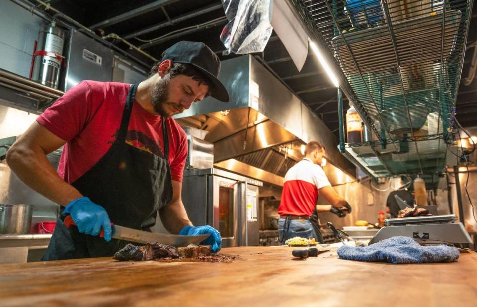 Kitchen manager Cruz Barnes cuts up chunks of burnt ends Thursday at Wolfepack BBQ in Columbus Park. The newly opened barbecue restaurant features brisket, burnt ends, ribs, and other barbecue staples. Zachary Linhares/zlinhares@kcstar.com