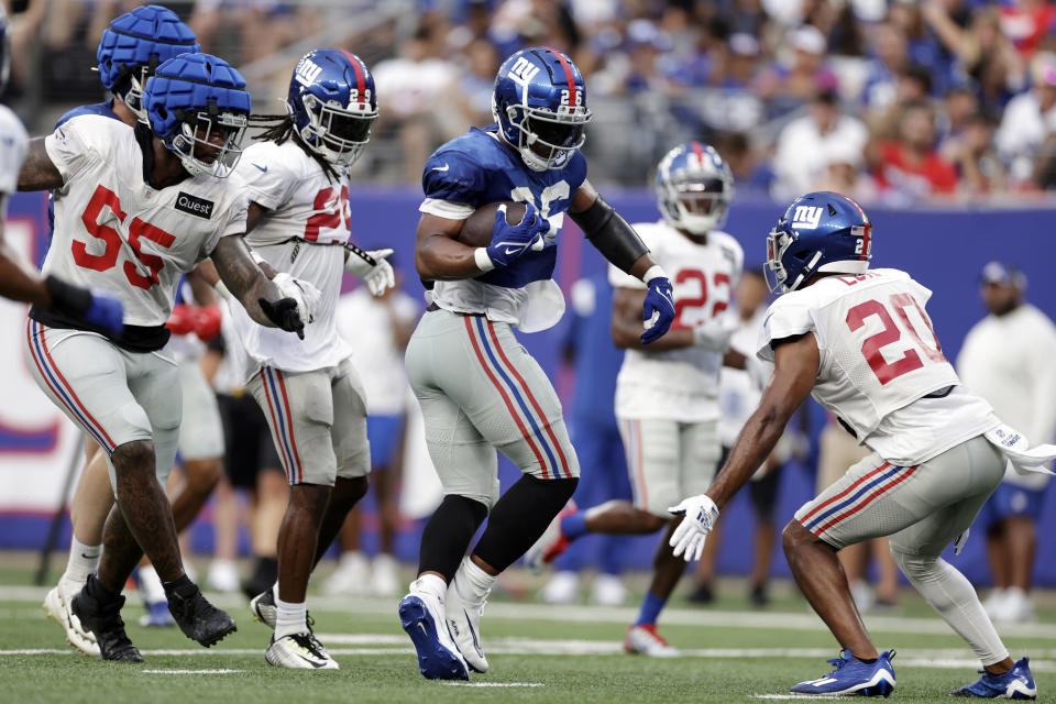 New York Giants running back Saquon Barkley (26) carries past safety Julian Love (20) during the NFL football team's practice in East Rutherford, N.J., Friday, Aug. 5, 2022. (AP Photo/Adam Hunger)